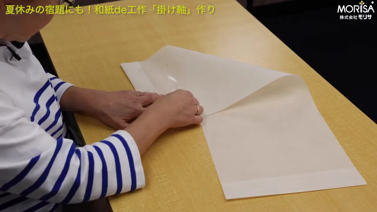 両面テープを少しずつ剥がしながら貼っている様子