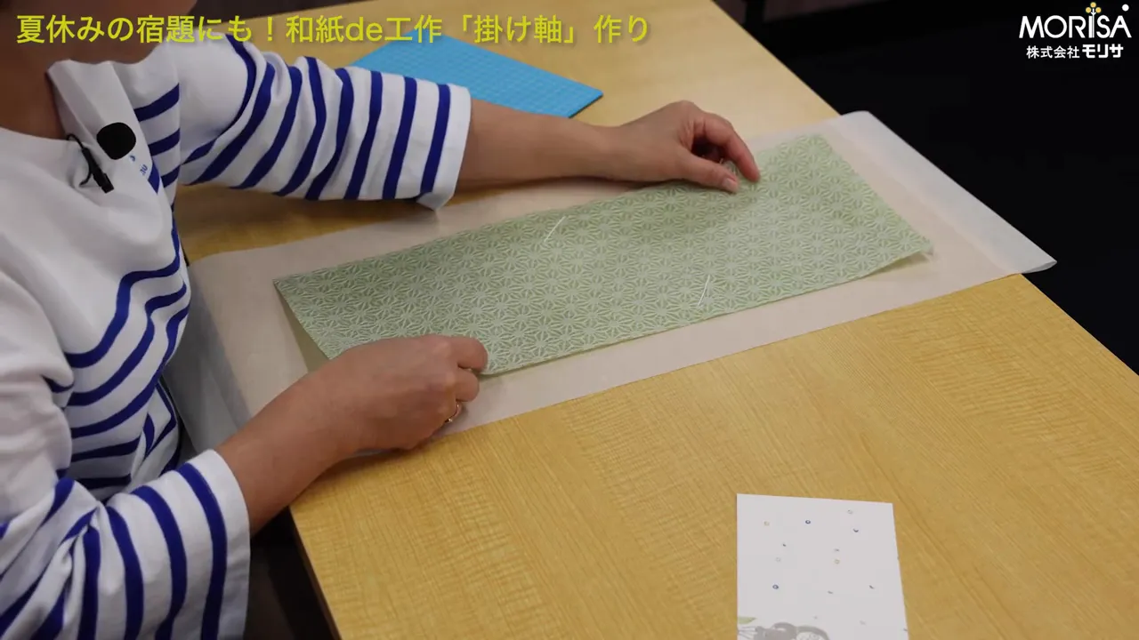 和紙の端を真っ直ぐに整えて貼り付けている場面