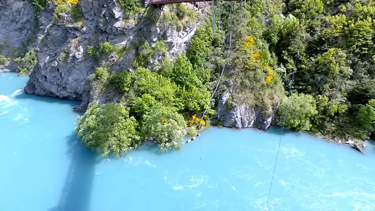 Turquoise, glacier-fed river flowing past rocky cliffs and green vegetation.