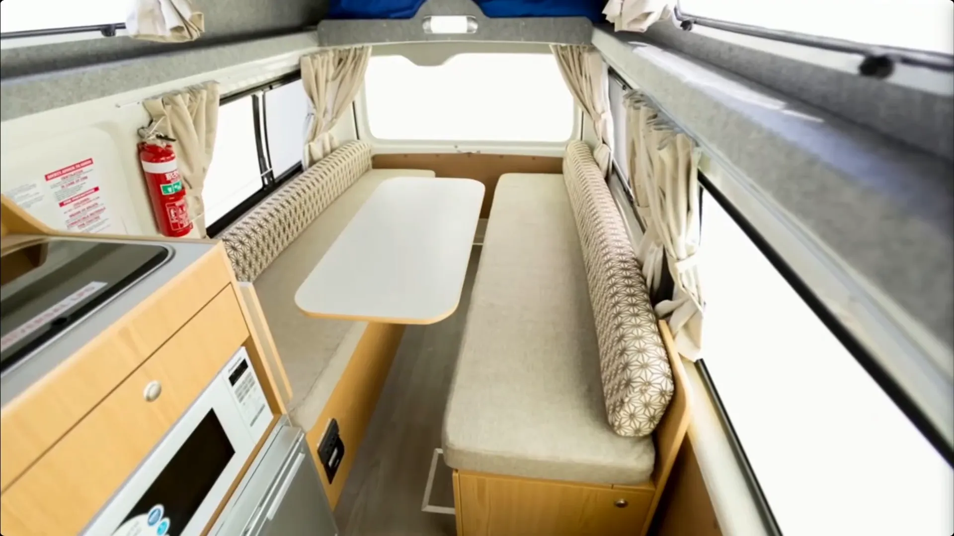 Interior of a compact campervan with fold-out bed and kitchenette