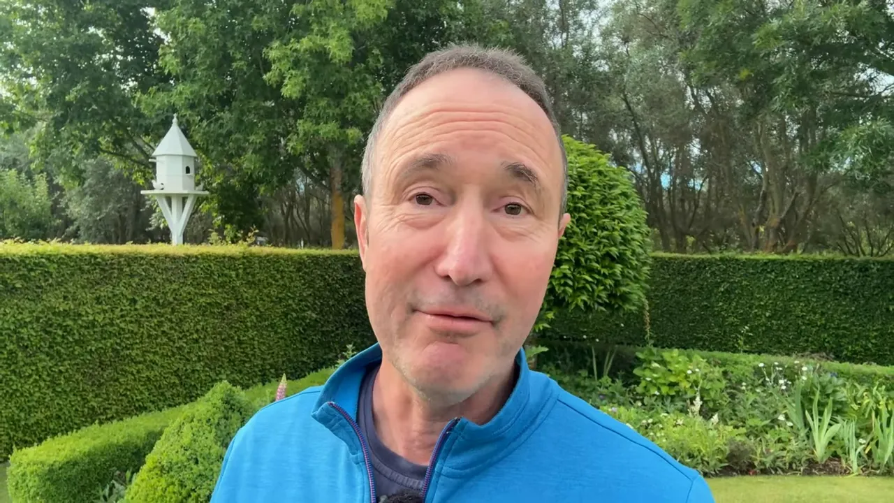 Presenter in front of formal cottage garden showing clipped hedges, round topiary and a white decorative birdhouse