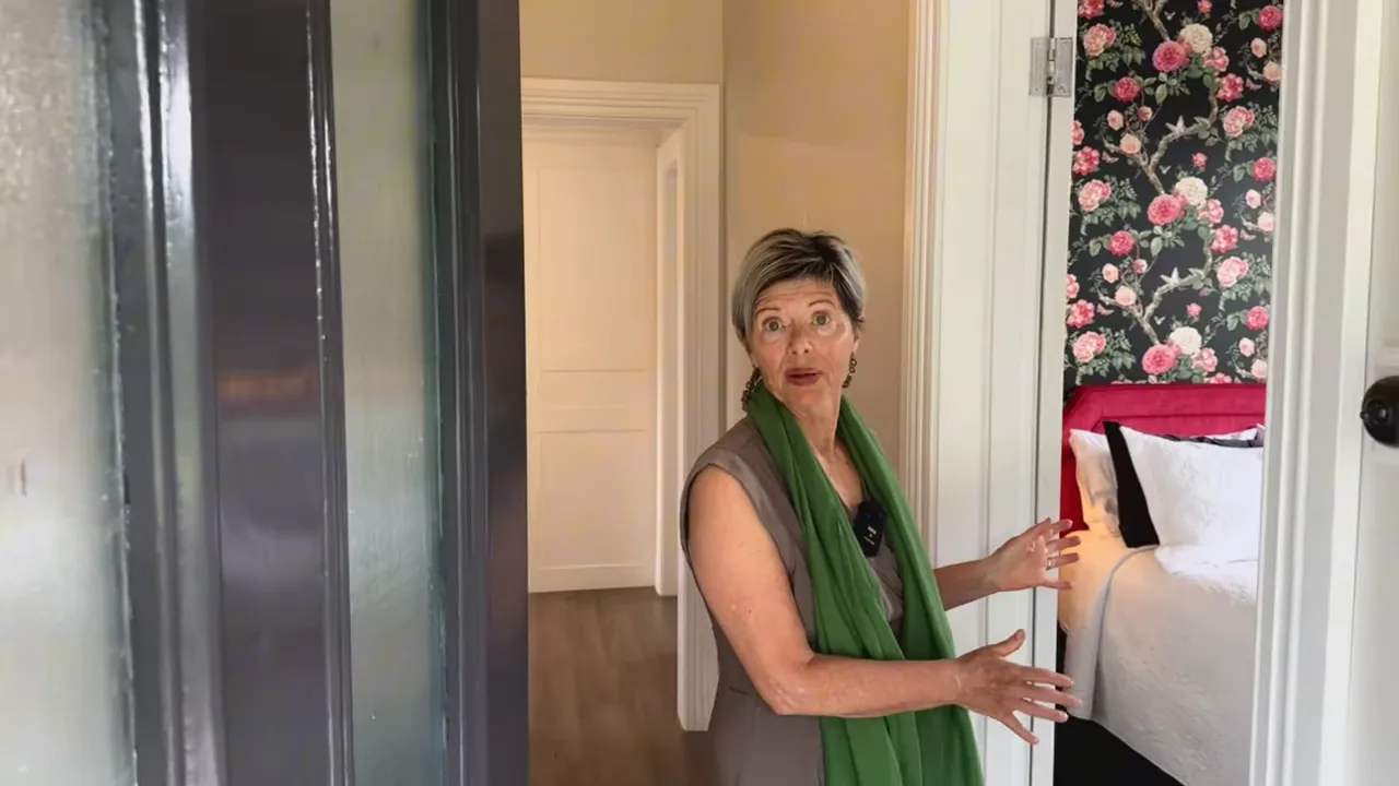 Host welcoming guests at Laurella Cottage entrance with bedroom visible