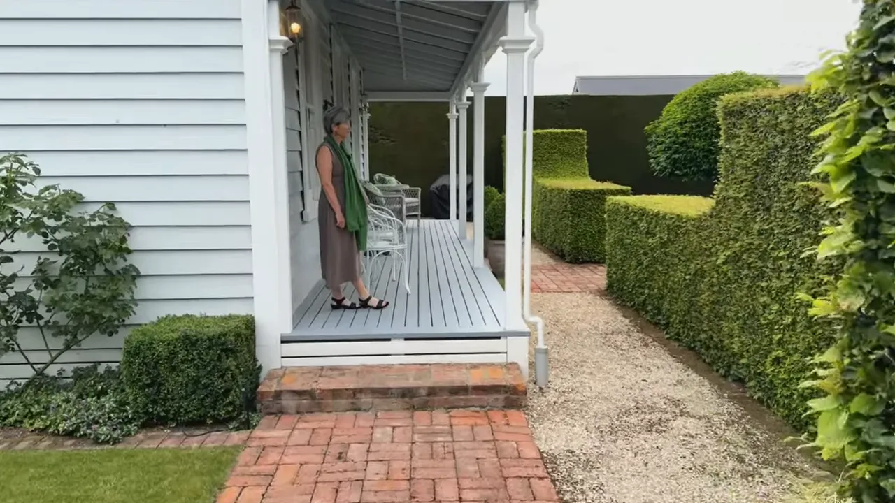 front veranda of a cottage with a path, brick steps and neatly trimmed hedges