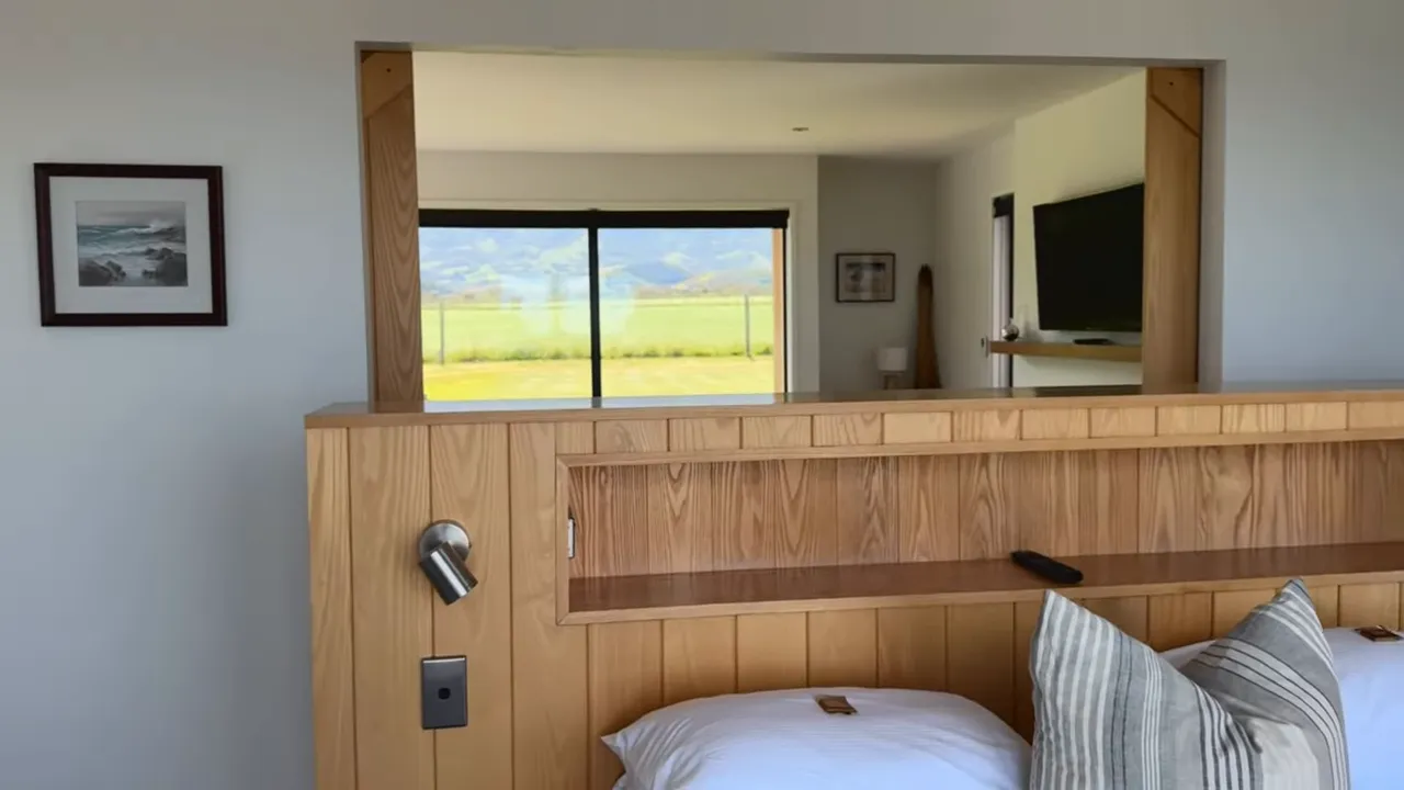 Timber partial wall separating bedroom and living area with wide opening and framed mountain view