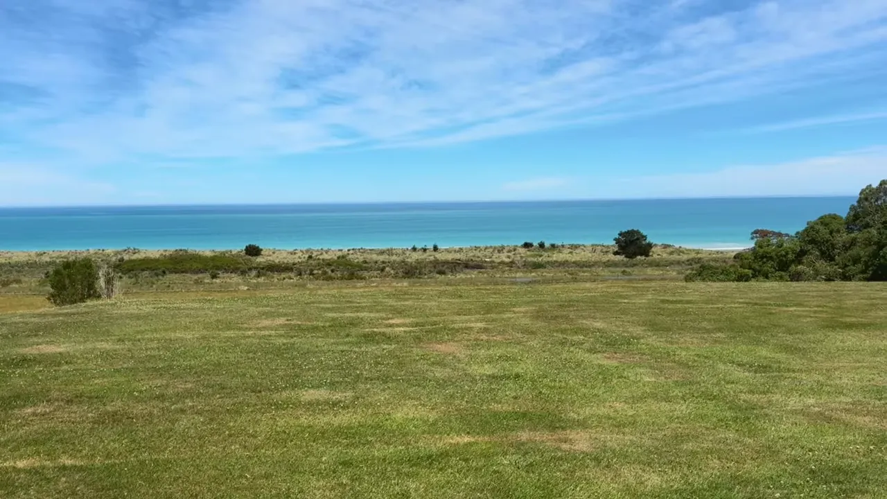 Grassy lawn leading to the Pacific Ocean with a clear blue sky at Glenburn Coastal Retreat