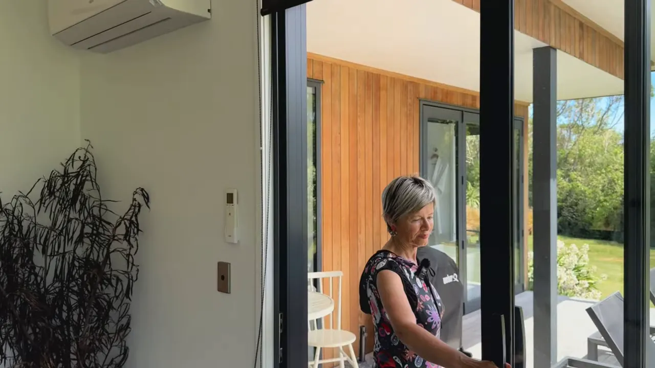 Guest opening sliding door onto veranda with loungers and Kaikoura Range in background