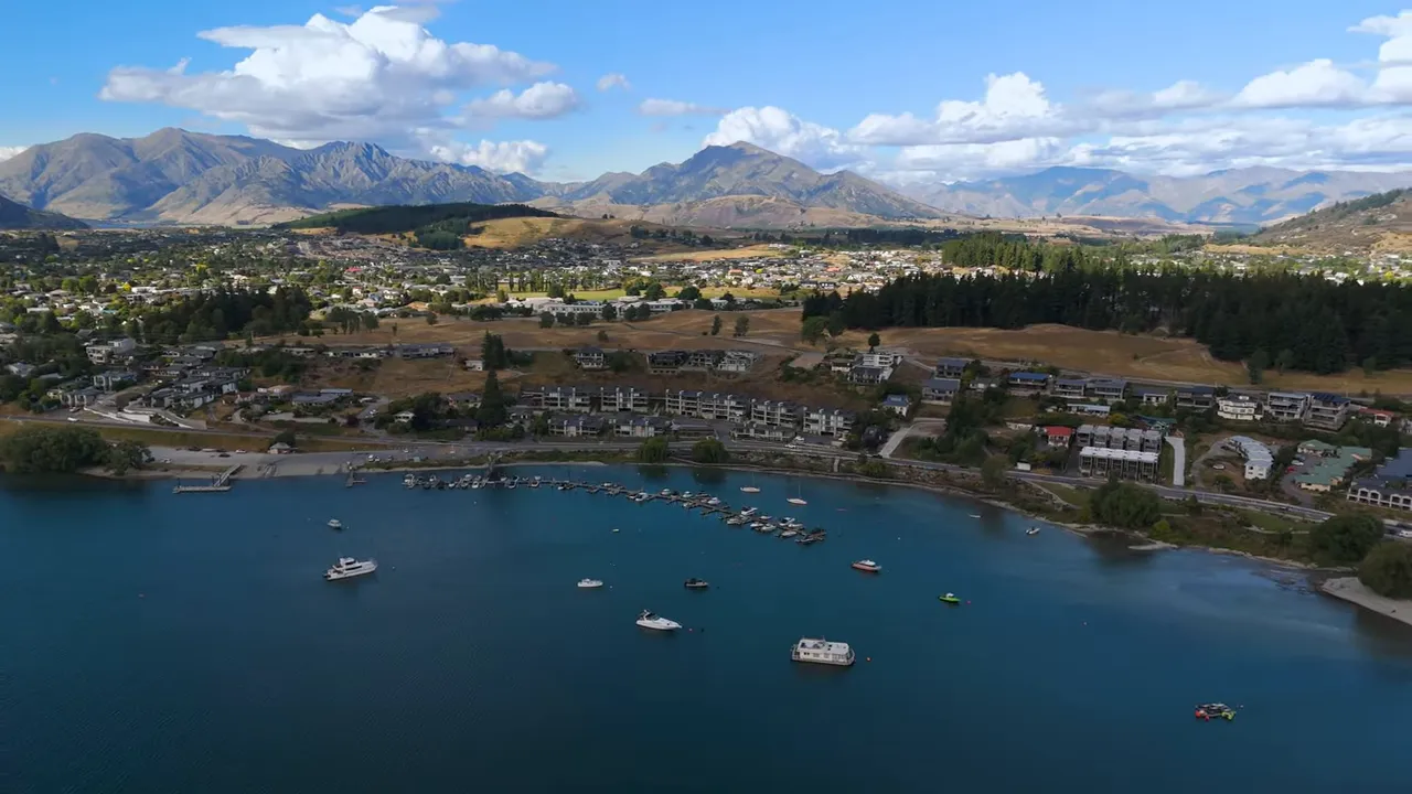 Aerial view of Wanaka town and Lake Wanaka with boats on the water and mountain ranges in the background