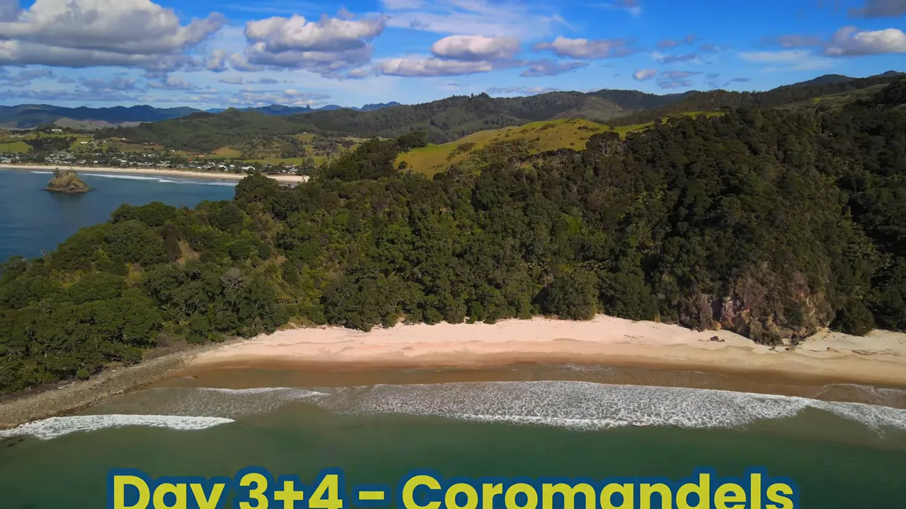 Aerial view of a sandy Coromandel beach with forested cliffs and turquoise water