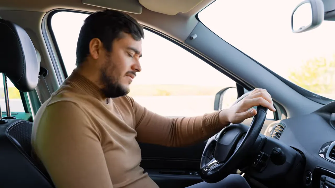 Person sitting in a car looking tired while holding the steering wheel