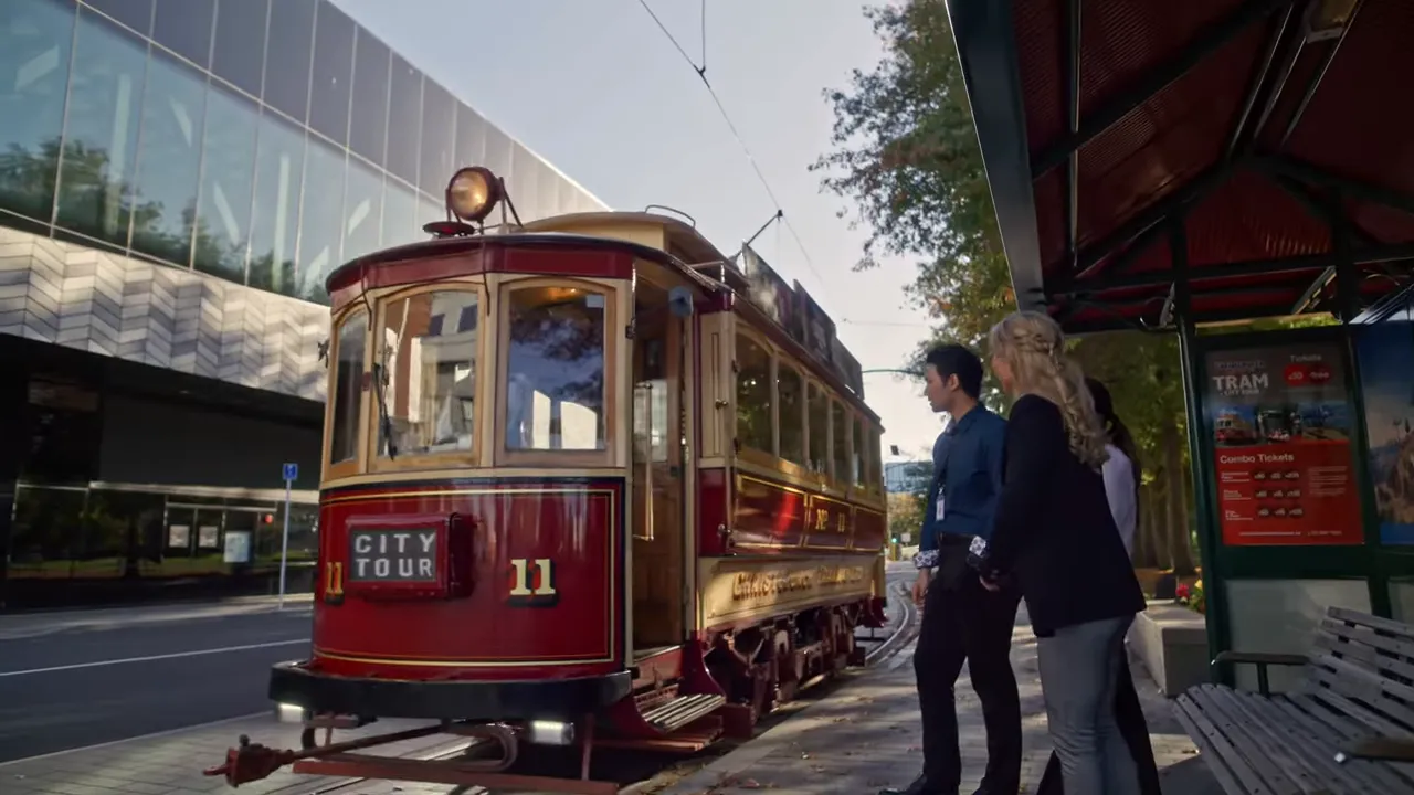 Vintage red Christchurch city tram at a tram stop with passengers boarding