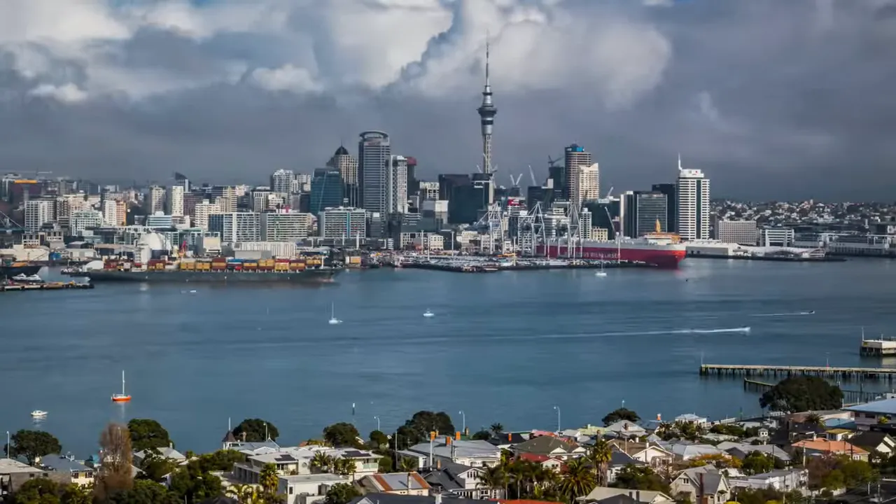 Wide Auckland harbour and skyline with Sky Tower under a cloudy sky