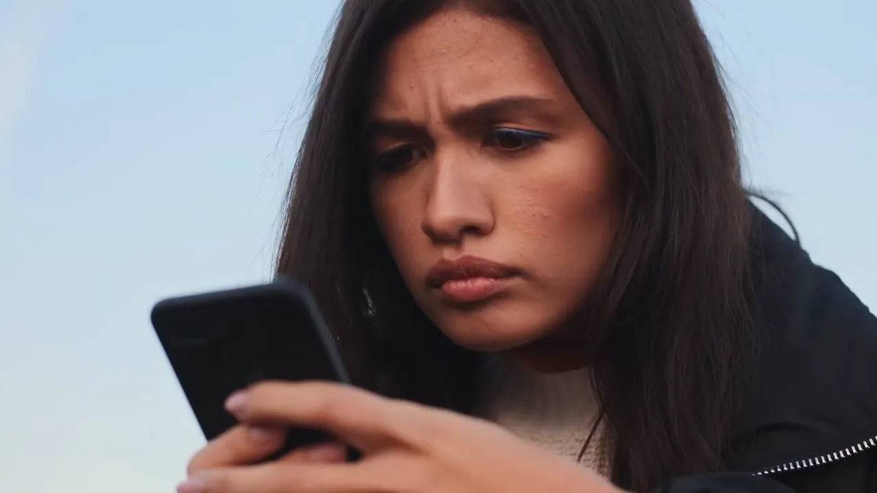 persona mirando su teléfono con expresión preocupada mientras revisa reseñas