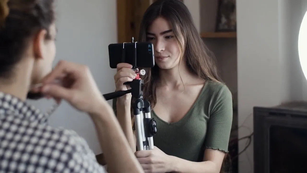 Persona grabando una reseña con teléfono montado en trípode y luz de anillo