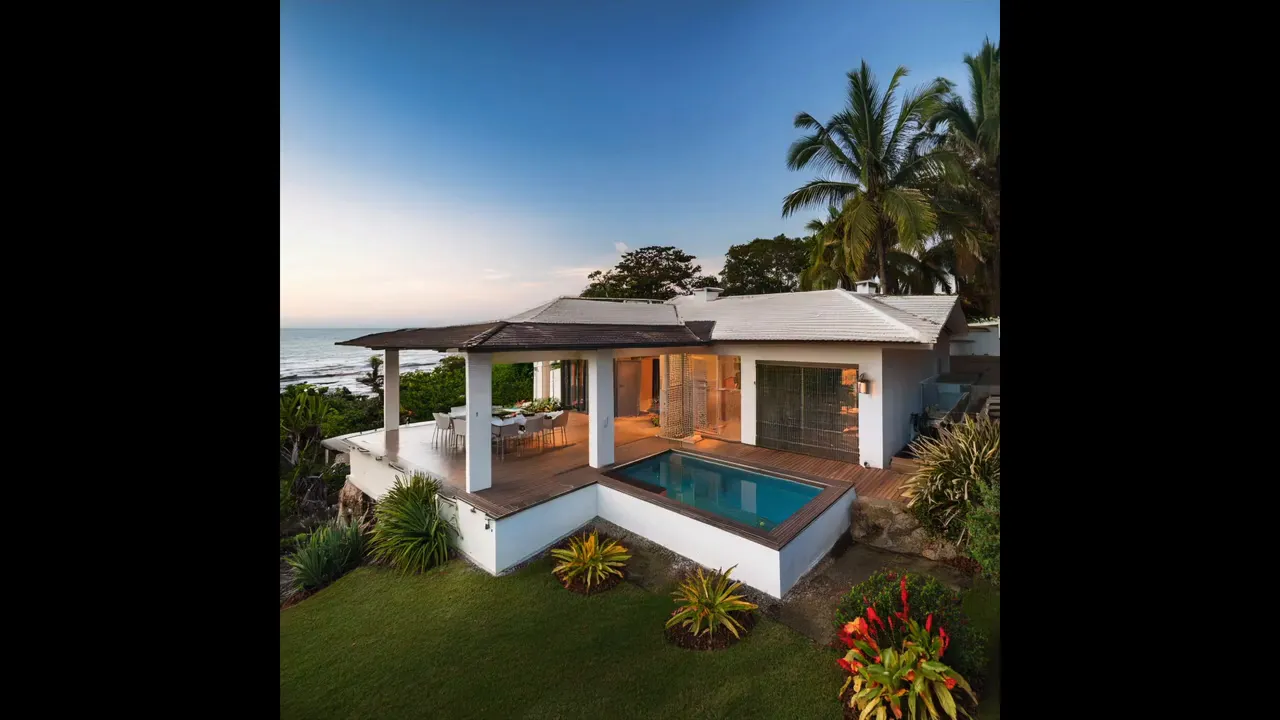 Large white multi-level hillside villa with expansive balconies and tropical vegetation