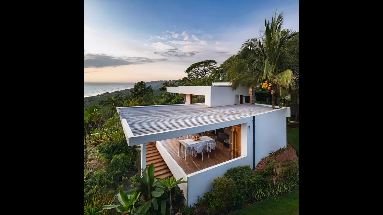 Large white modern villa with long pool and broad terrace on a hillside