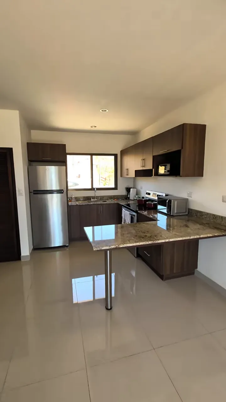 Kitchen with refrigerator, dark cabinets, range, microwave, and projecting countertop