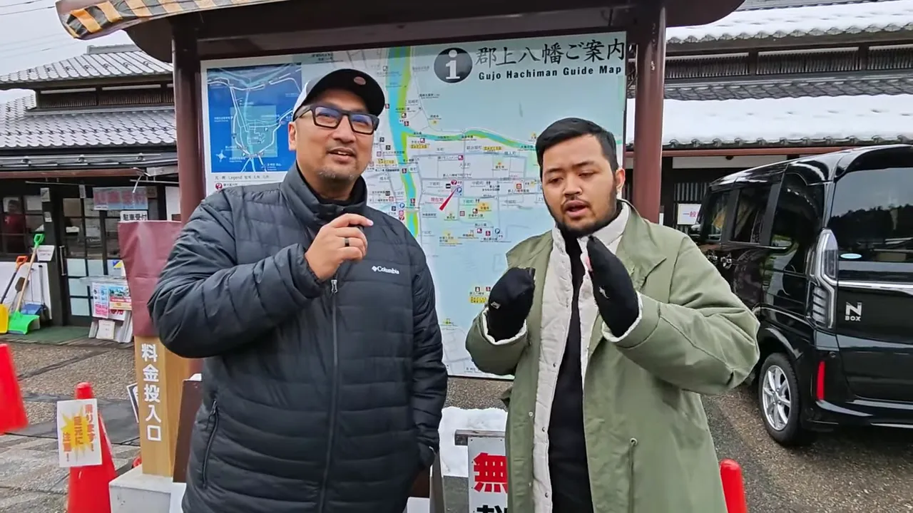 Dua reviewer berdiri di depan peta panduan Gujo Hachiman sambil menjelaskan bantalan midsole sepatu