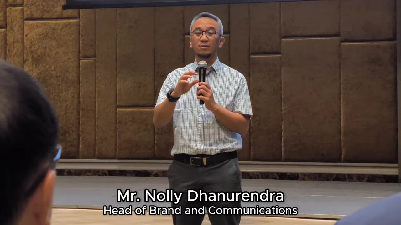 Pembicara berdiri di panggung menjelaskan poin sambil memberi gestur