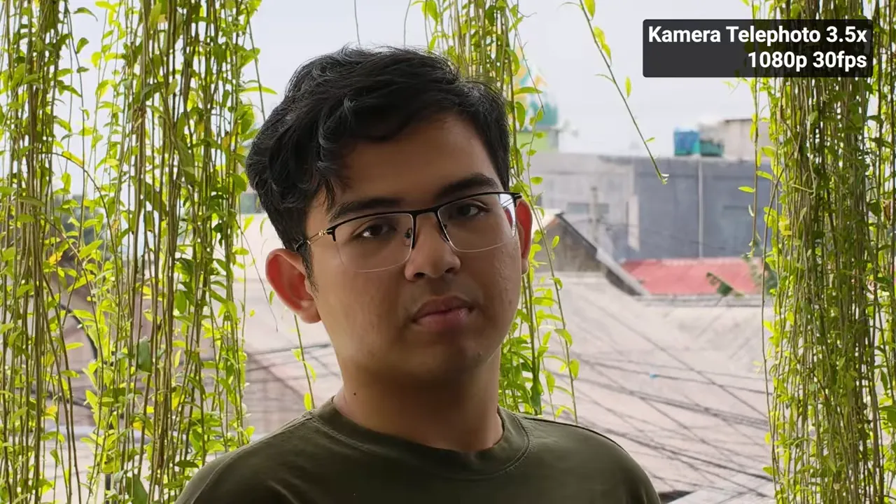 Contoh perekaman telephoto OPPO Reno15 Pro Max 3.5x 1080p30 menampilkan potret subjek di depan latar tanaman dengan overlay teks 'Kamera Telephoto 3.5x 1080p 30fps'.