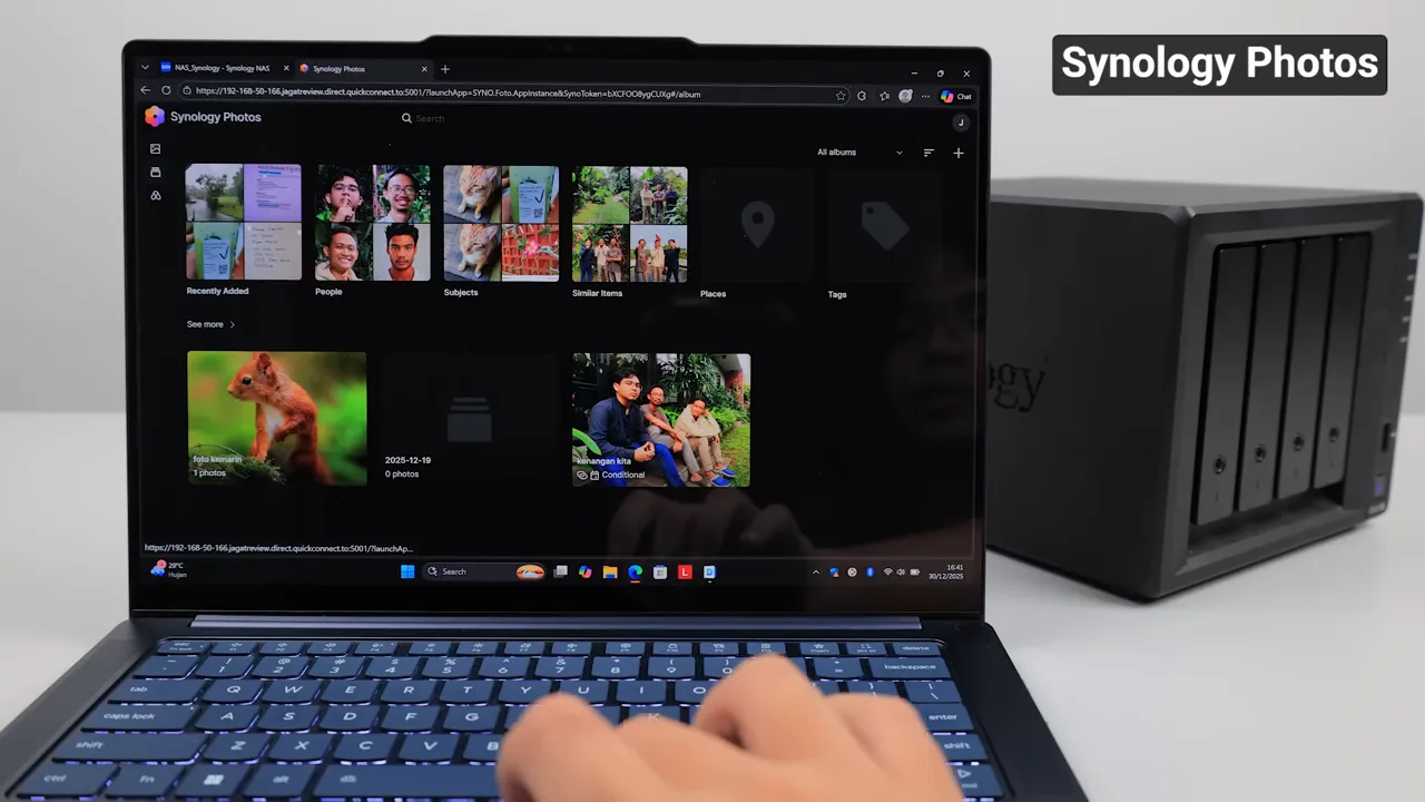 Antarmuka Synology Photos menampilkan album dan thumbnail foto di layar laptop dengan unit NAS Synology DS925+ di latar belakang