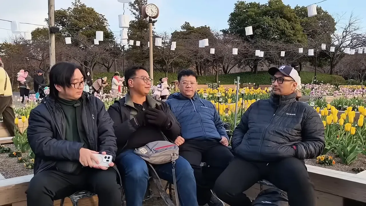 Empat orang duduk di bangku taman di depan kebun tulip, pencahayaan baik dan fokus jelas