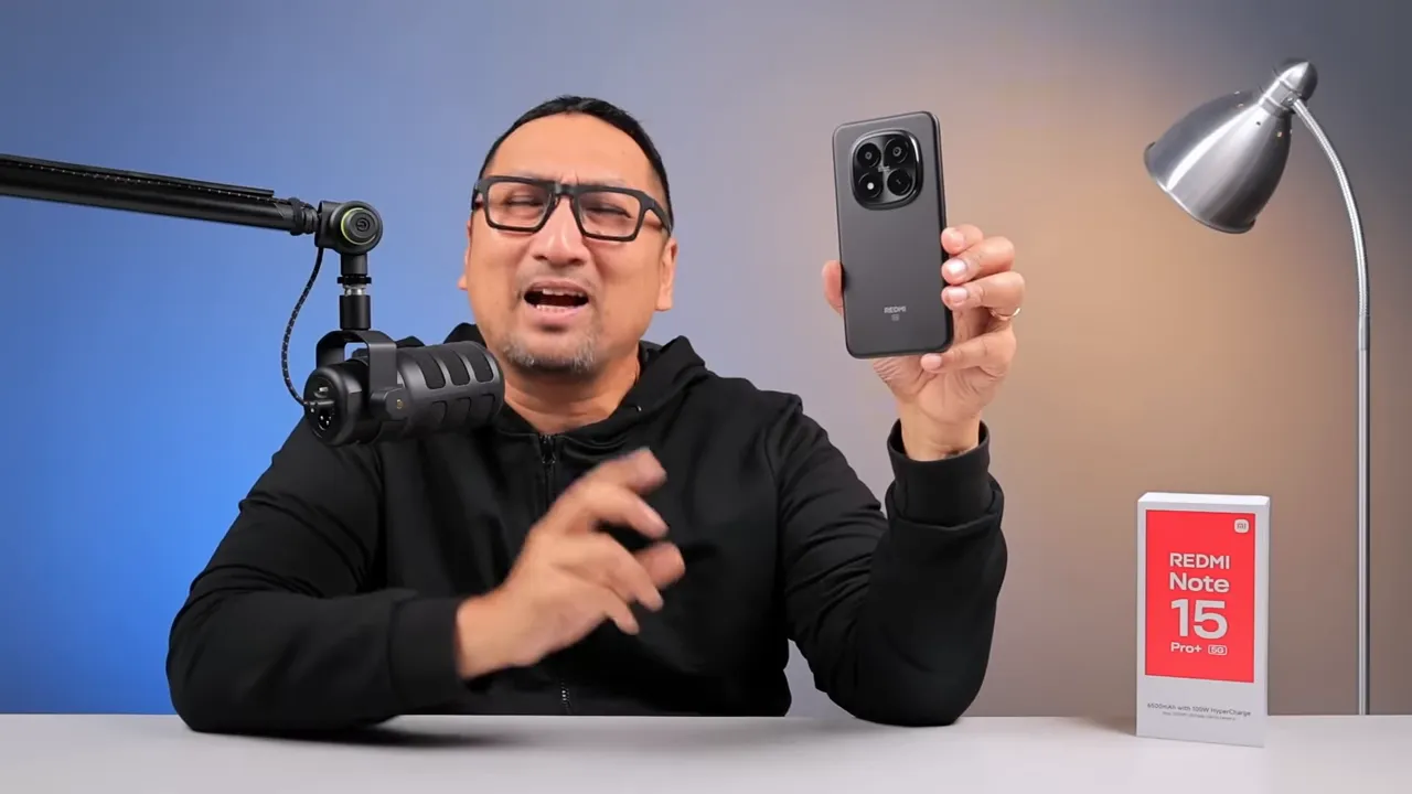 Reviewer memegang Redmi Note 15 Pro+ dengan kotak penjualan di meja