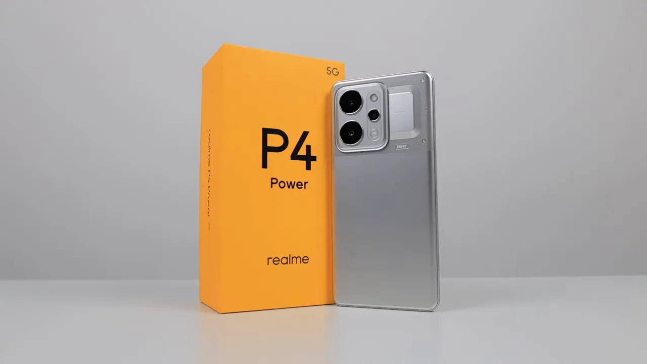Close-up Realme P4 Power berdiri di samping kotak oranye di latar abu-abu