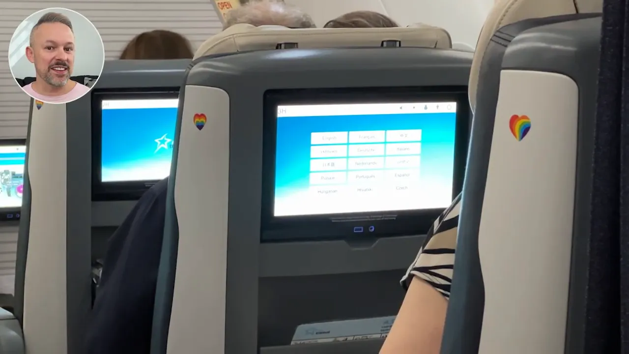 Airline seatback entertainment screens with small rainbow-heart stickers on the seat shells.