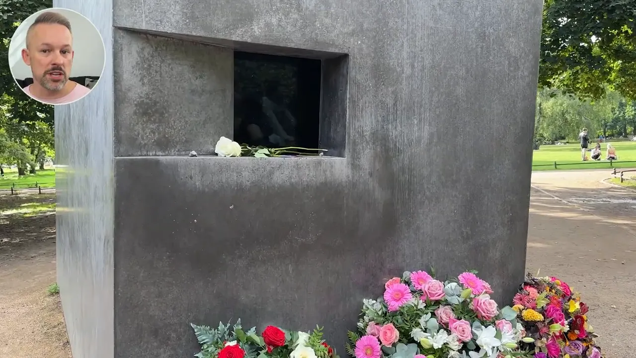 Close-up of the memorial cube's small viewing window with flowers laid at its base