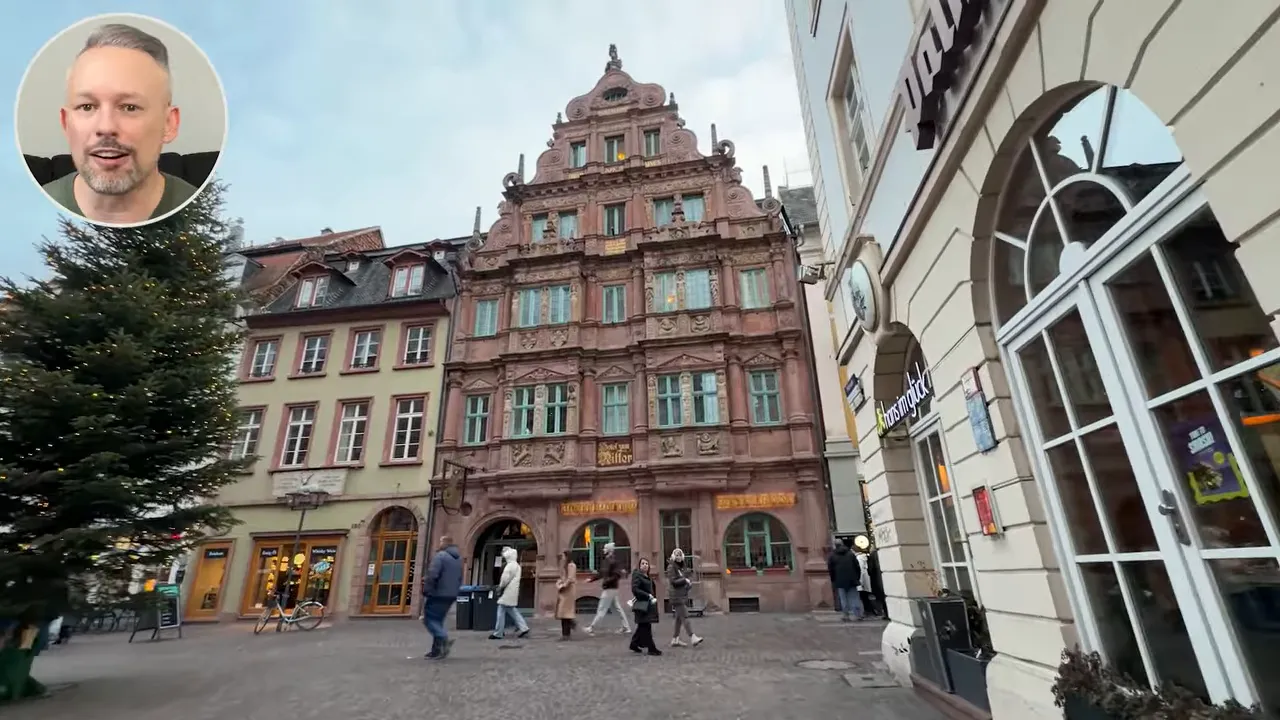 Ornately carved multi‑story sandstone building (Haus zum Ritter) in Heidelberg’s Altstadt with a decorated Christmas tree and pedestrians on the cobbles.