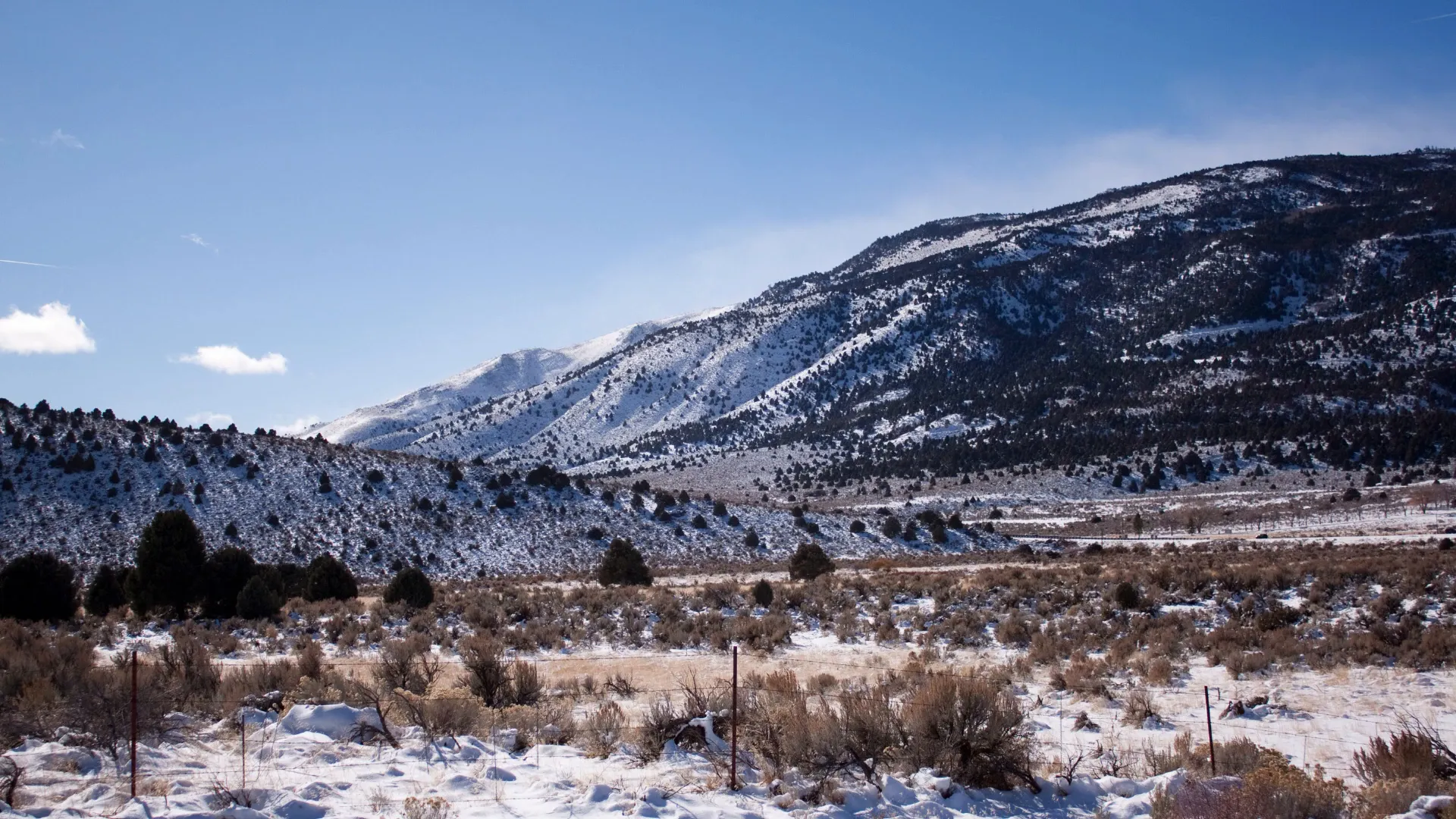 Snow-dusted mountains and sagebrush under a bright blue sky