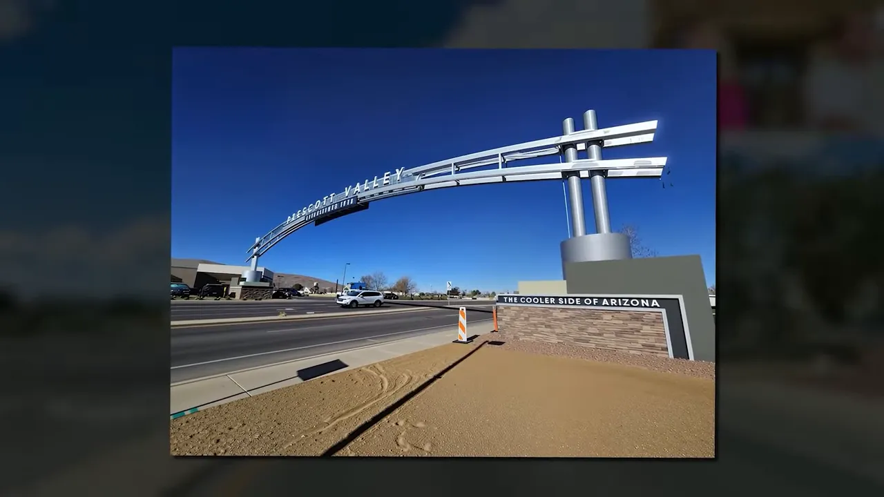 Prescott Valley gateway arch over Glassford Hill Drive against a deep blue sky, with road and sidewalk visible.