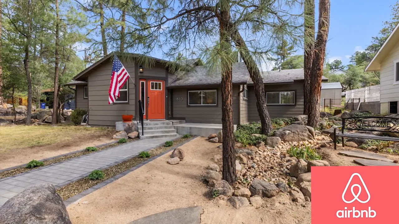 Vacation rental home exterior with front yard, pine trees, and Airbnb logo