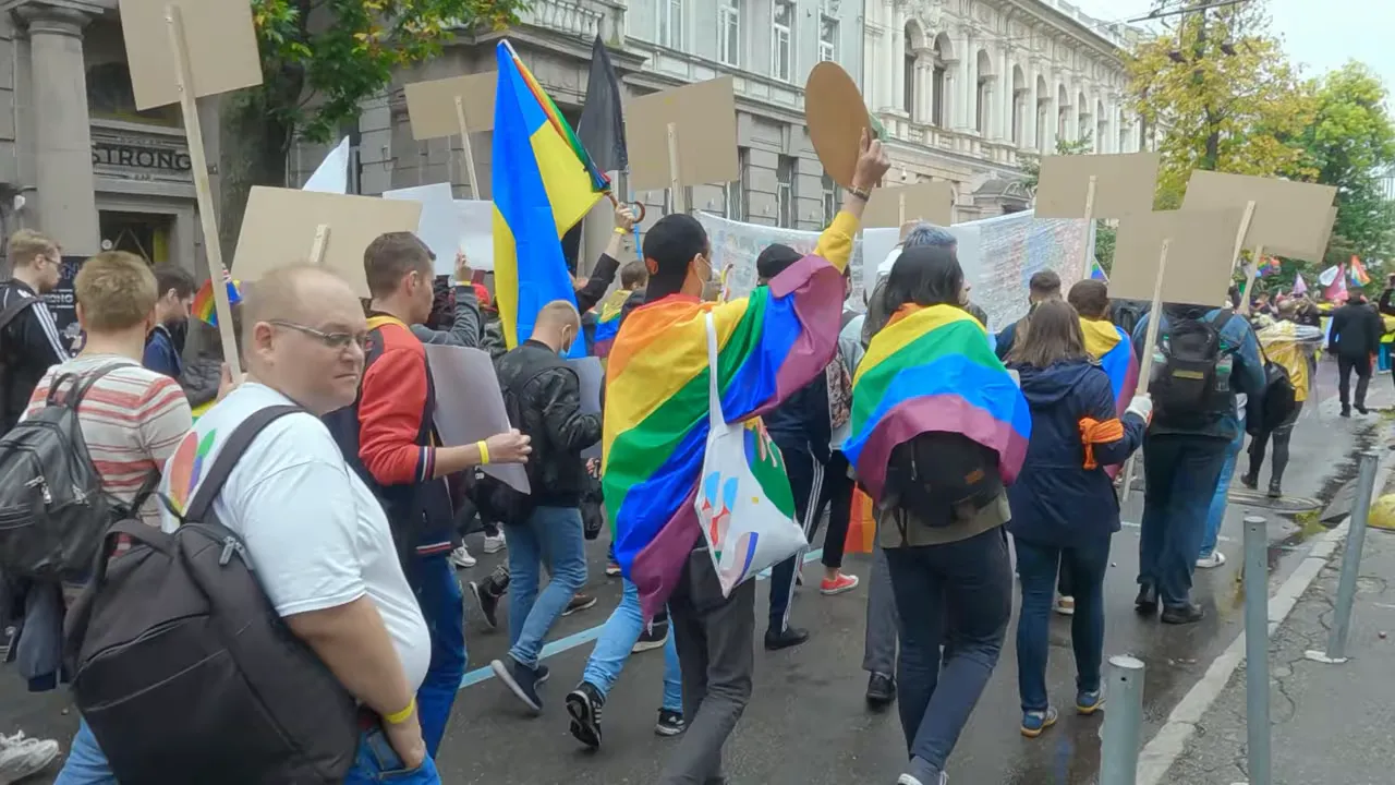 Crowd marching in the street holding colorful flags and banners during a political demonstration