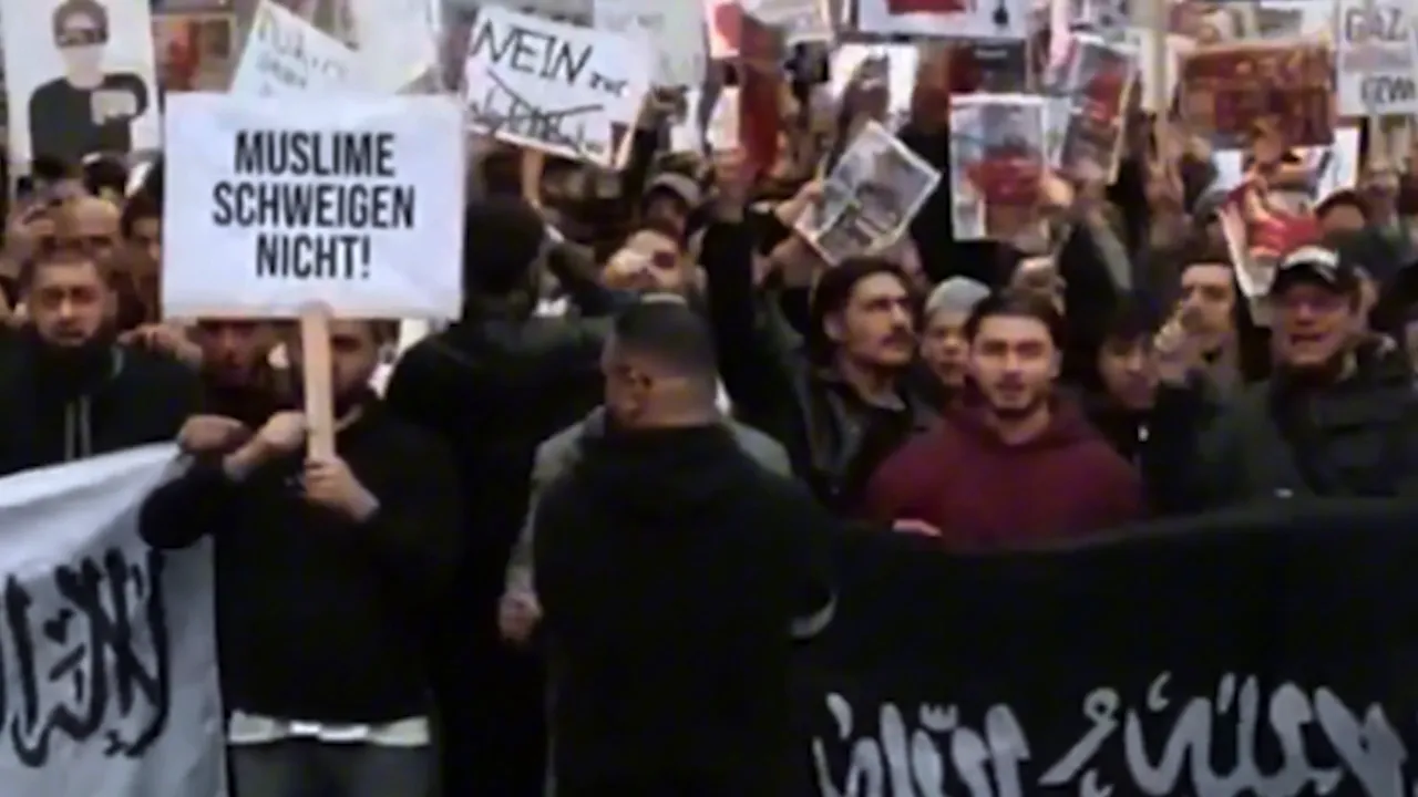 Large group of protesters with signs and black banners in a street march