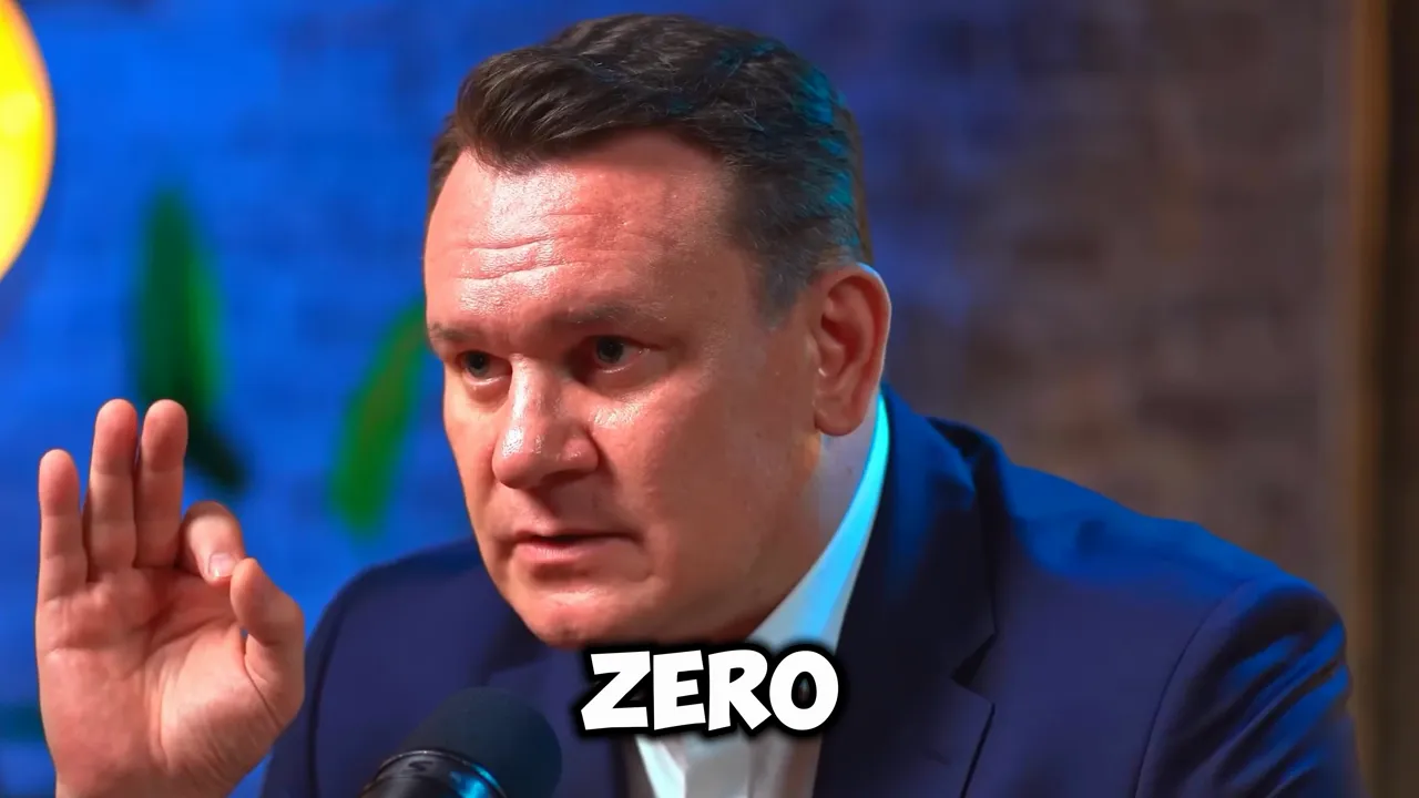 Close-up of a male speaker gesturing emphatically into a microphone with the word 'ZERO' overlaid