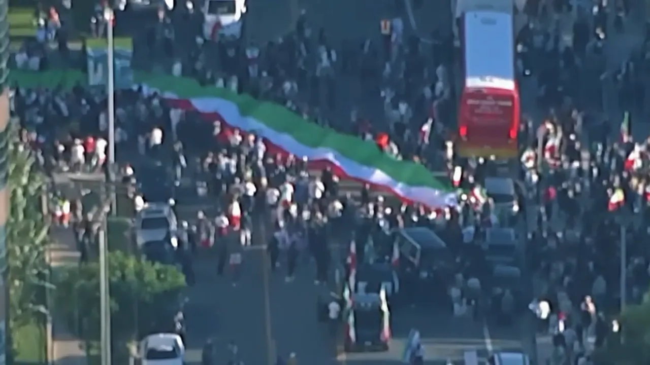 Aerial view of a crowded street protest with a long green-white-red banner