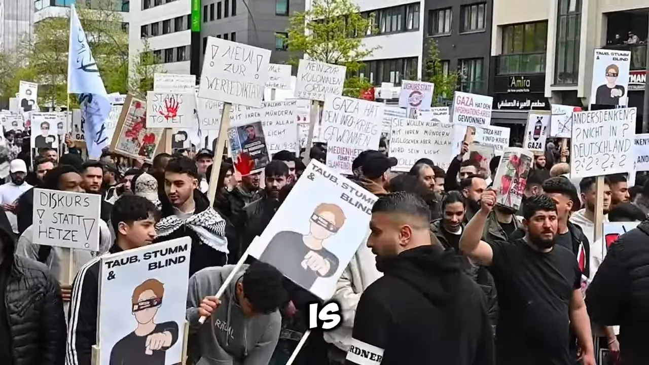 Crowd at a protest holding placards with political messaging and Arabic/German text