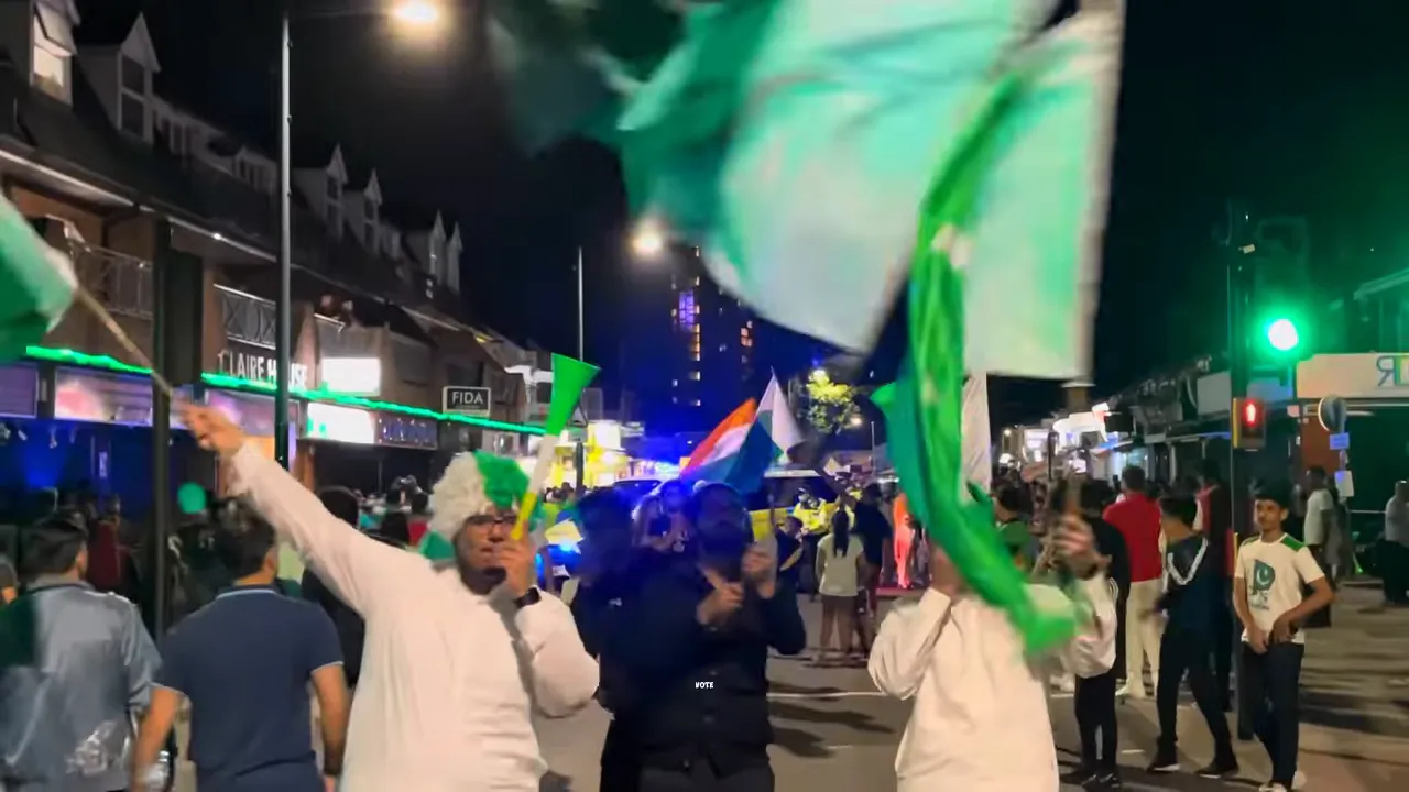 Nighttime street crowd waving green and white flags