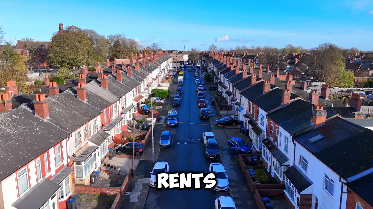Aerial view of a long residential street with tightly packed houses and parked cars