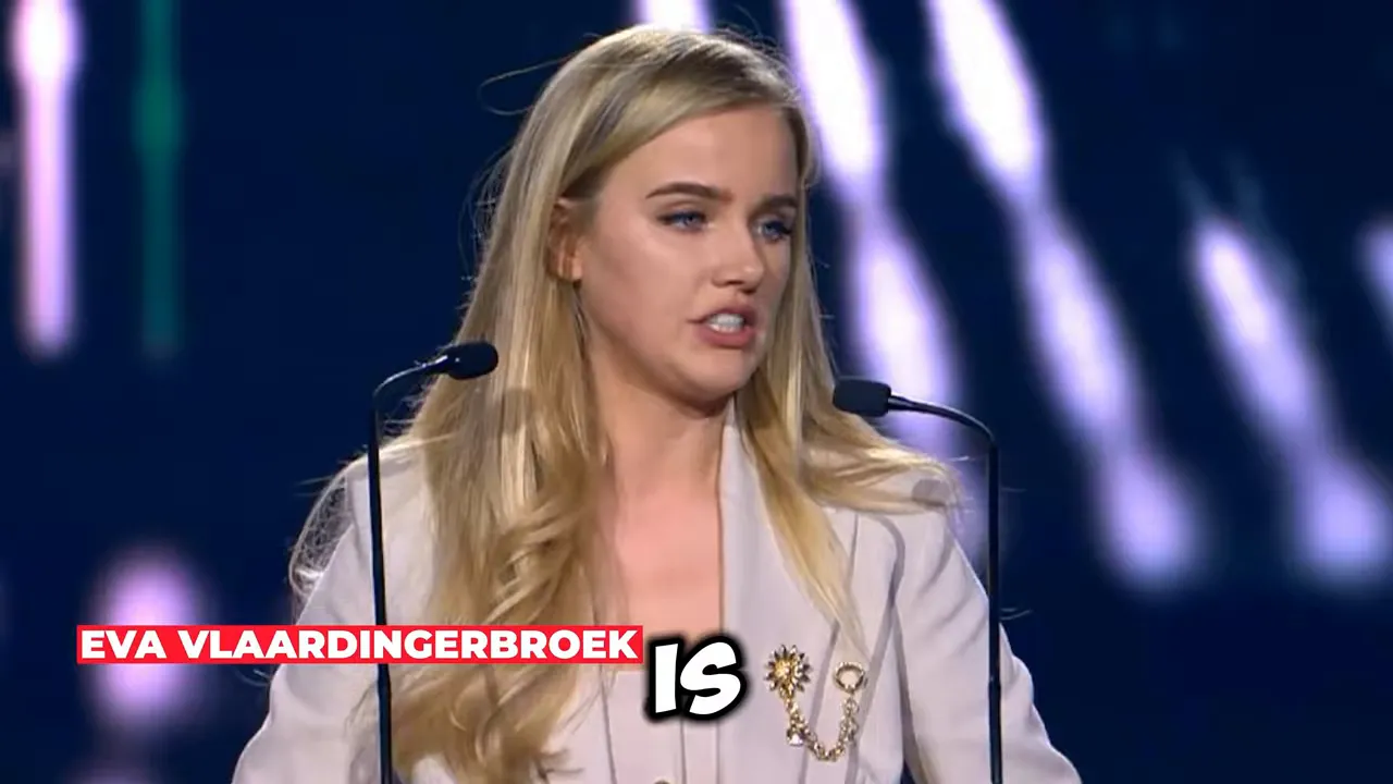 Presenter at a conference podium with on-screen text reading “IS”