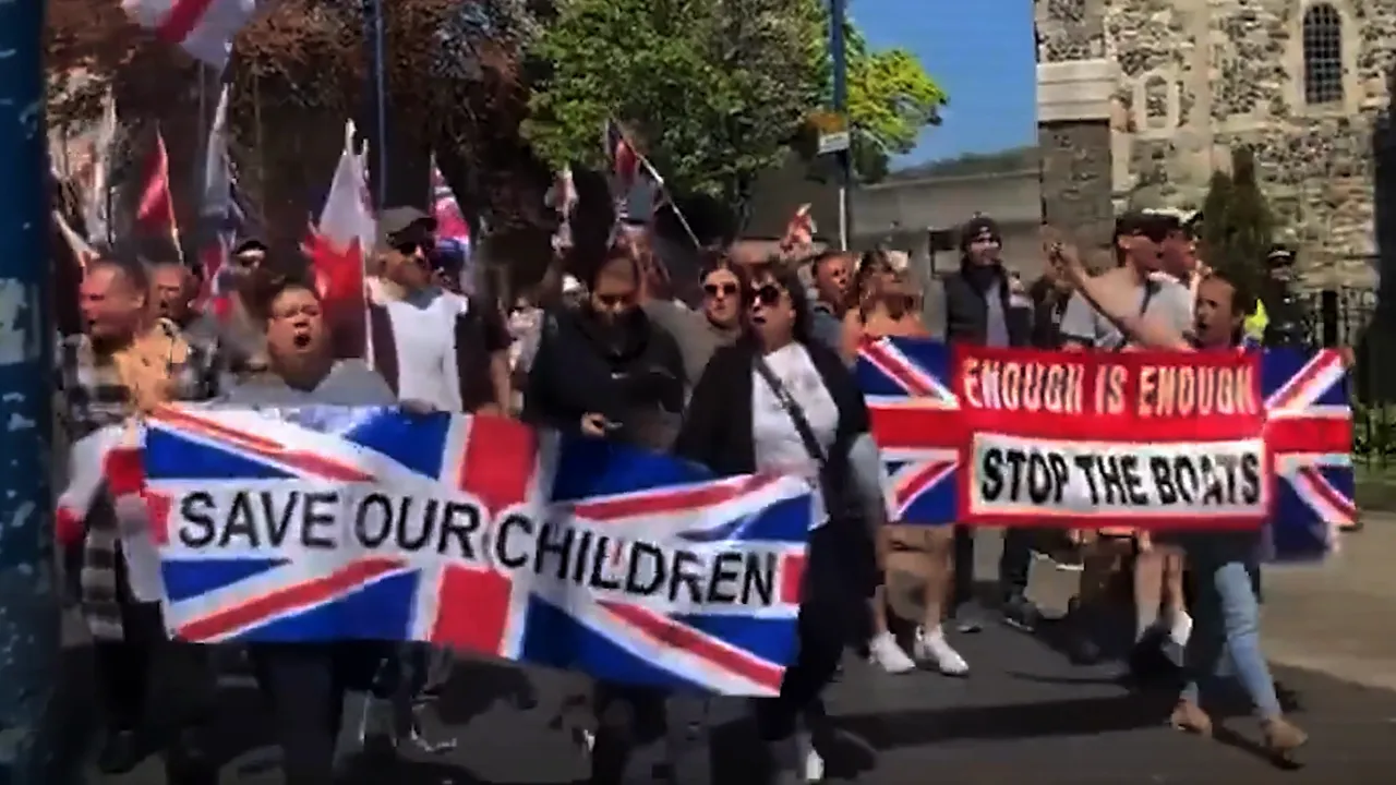 Protesters holding Union Jack banners reading 'SAVE OUR CHILDREN' and 'STOP THE BOATS' marching in a street demonstration