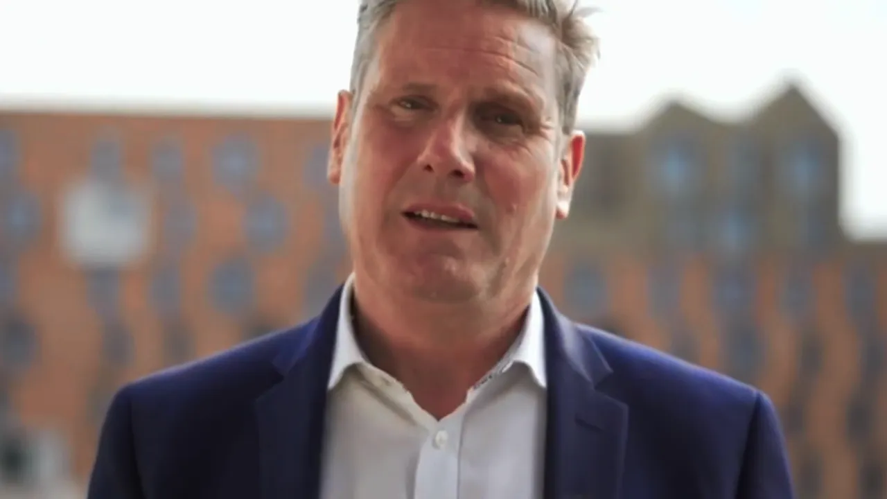 Man in a suit speaking outdoors with a blurred urban background