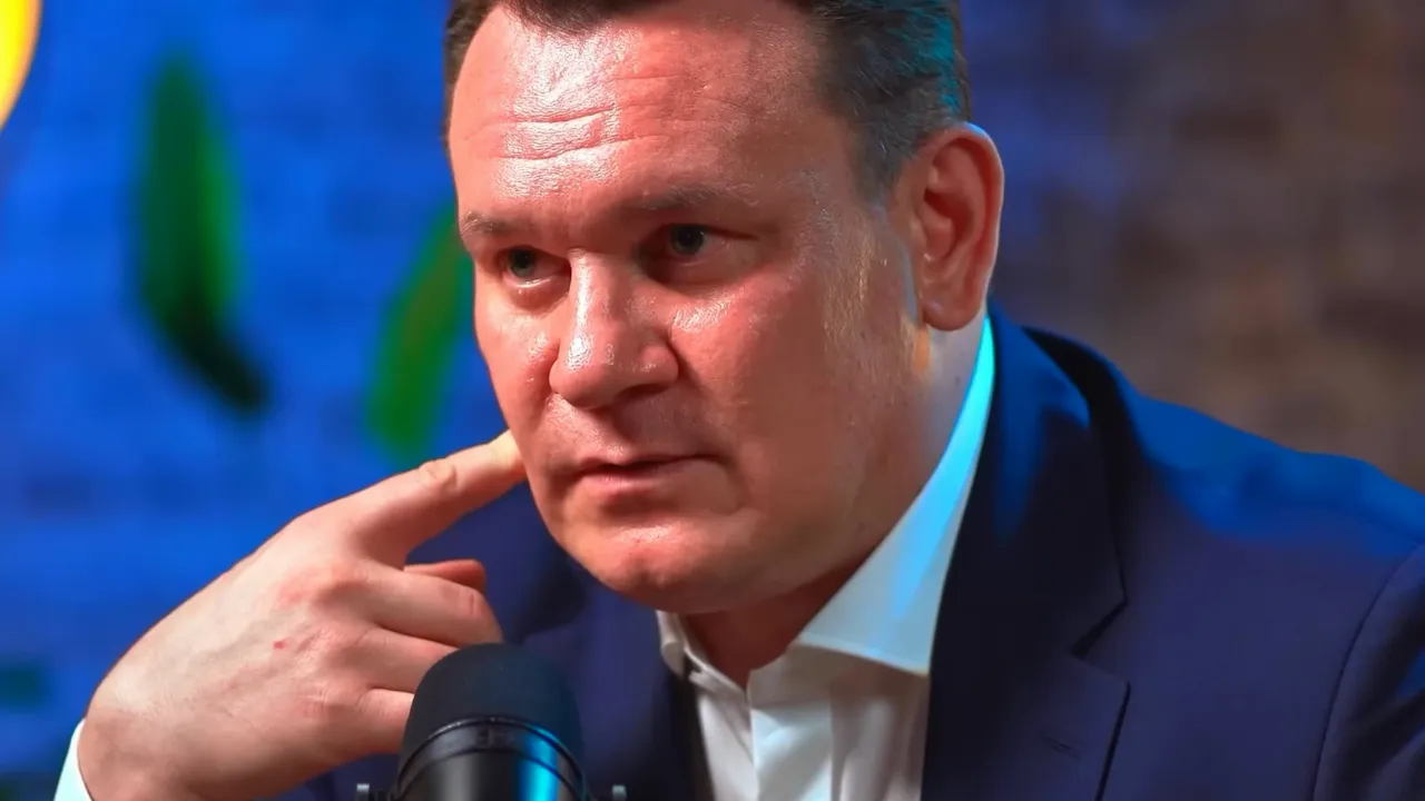 Mid-shot of podcast guest pausing and touching his face while speaking into a microphone