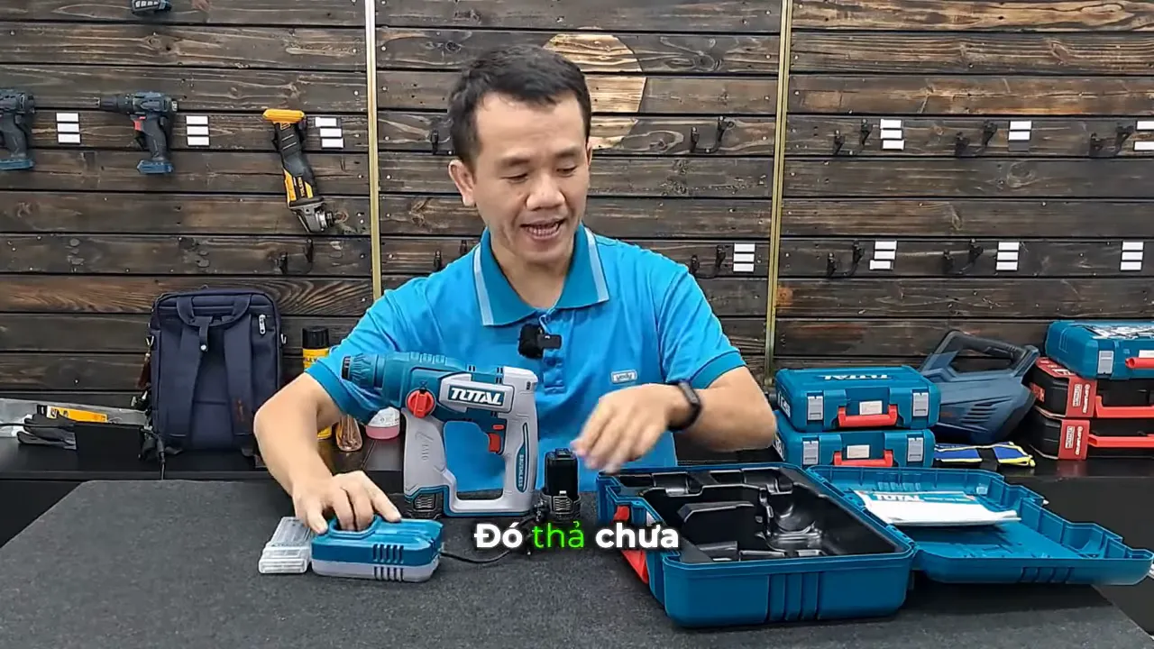 Hộp phụ kiện Total mở, thân máy khoan, bộ sạc và pin đặt trên bàn