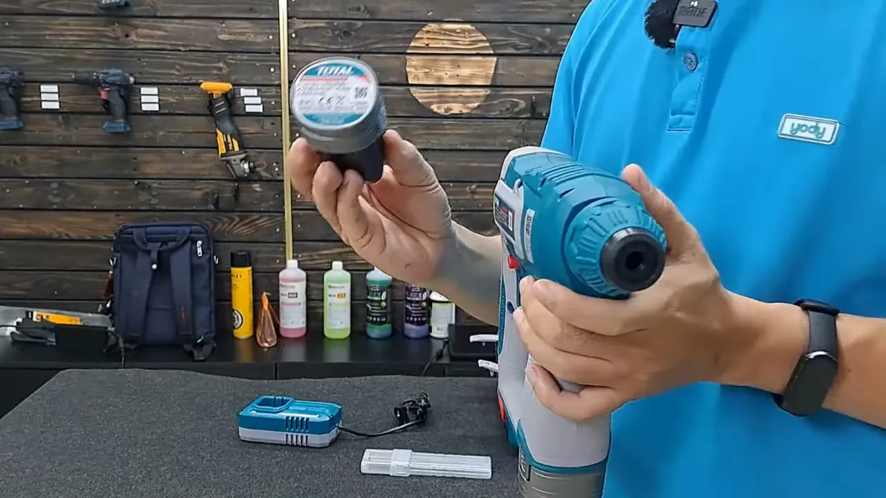 Người cầm viên pin 16V8 của Total trước thân máy khoan, bộ sạc và phụ kiện đặt trên bàn