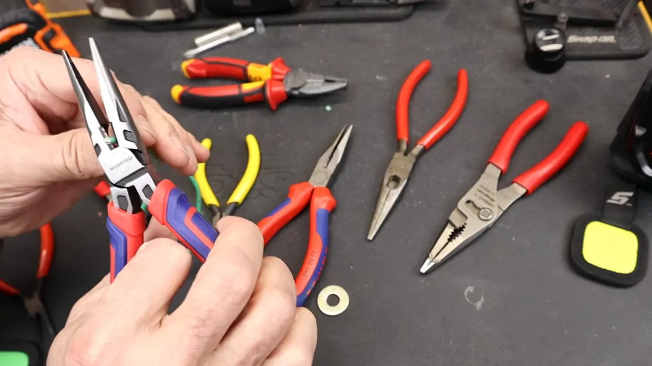 Kìm mỏ nhọn Workpro đang kẹp và cắt dây trên bàn dụng cụ