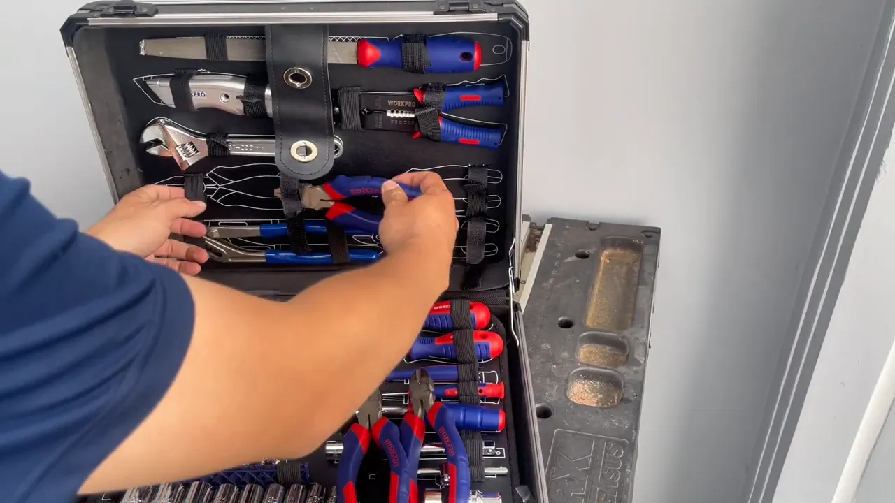 Tầng trên vali WorkPro hiển thị nhiều loại kìm và dao rọc, người đang chỉnh kìm