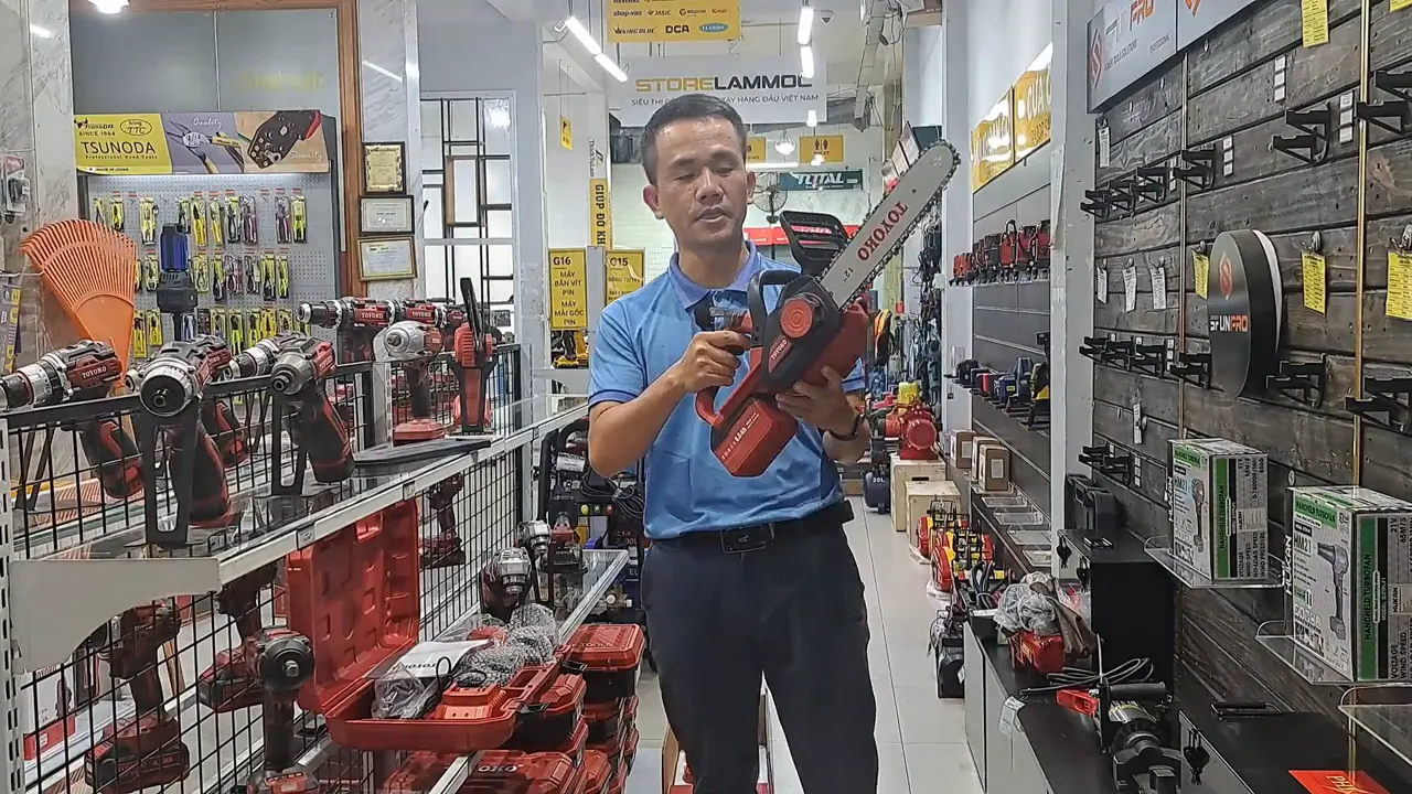 Nhân viên cầm máy cưa xích TOYOKO, thấy rõ lam 12 inch và thân máy màu đỏ