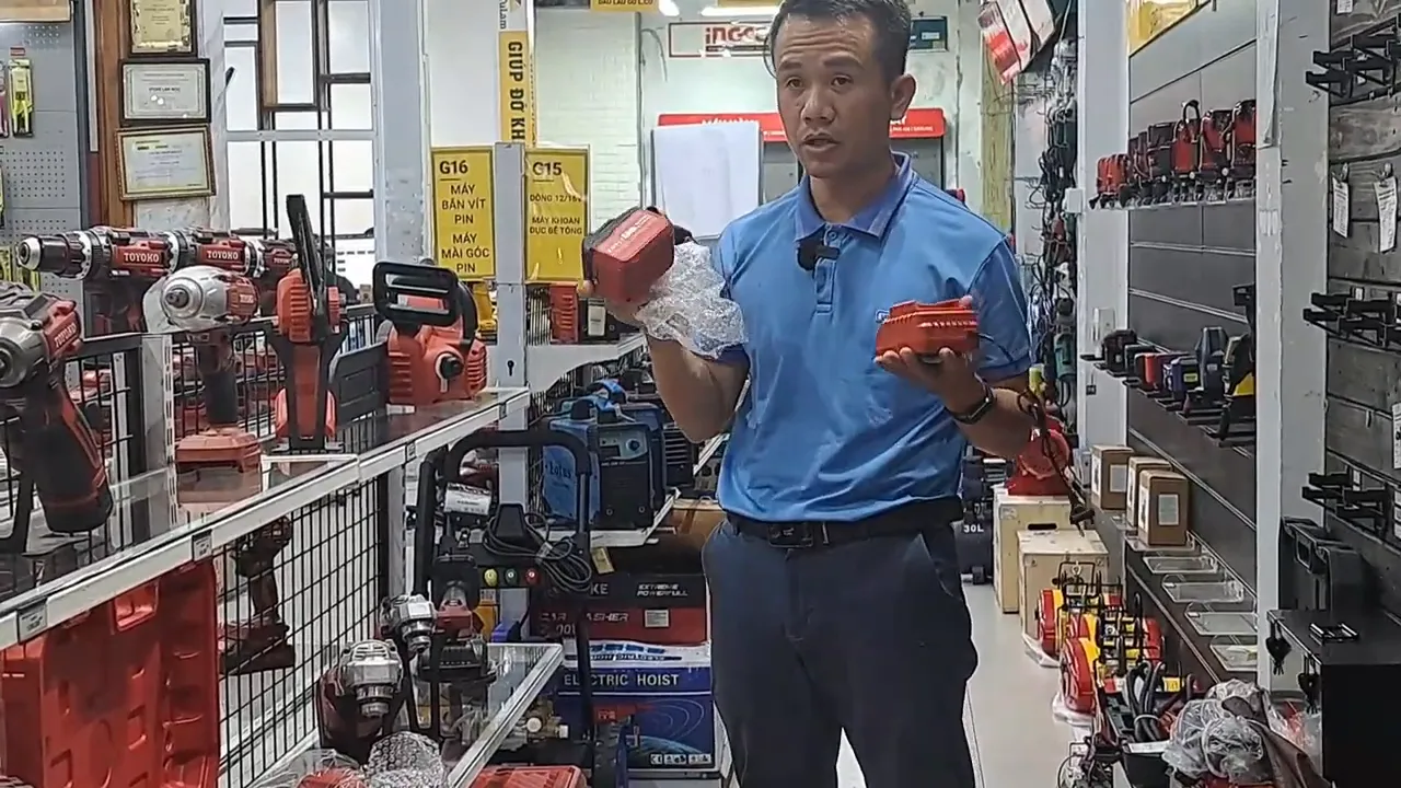 nhân viên cầm hai bộ pin/linh kiện bọc màng bong bóng để minh họa phụ kiện